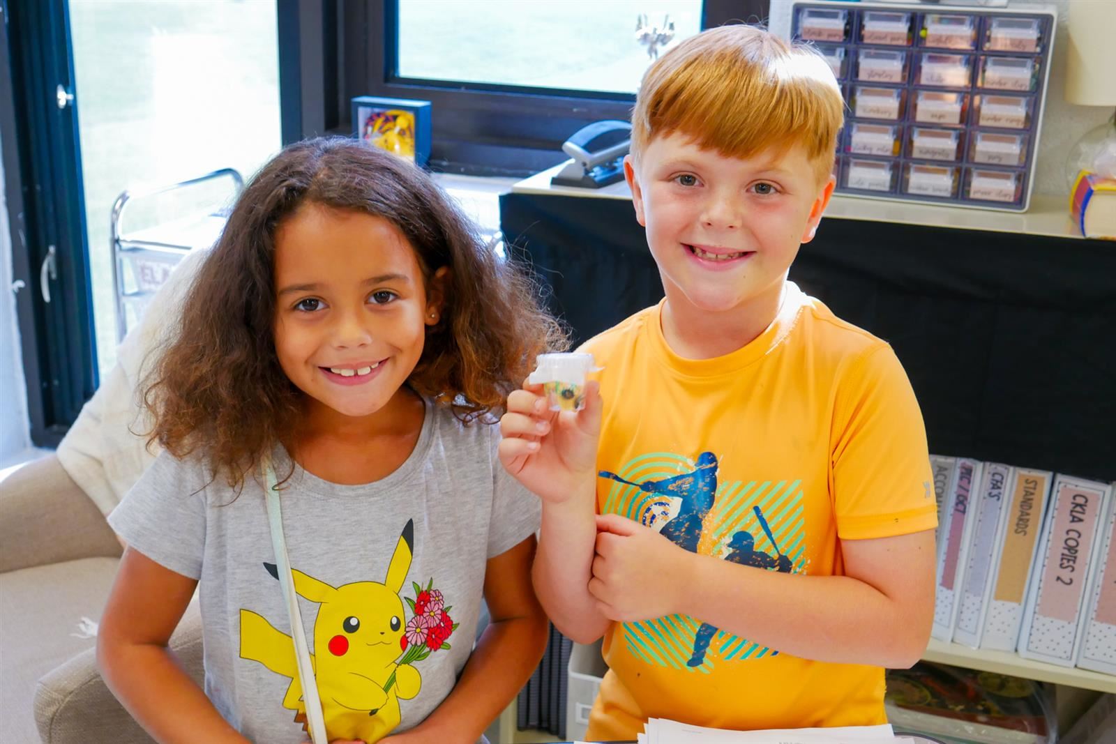 Two students holding up caterpillar